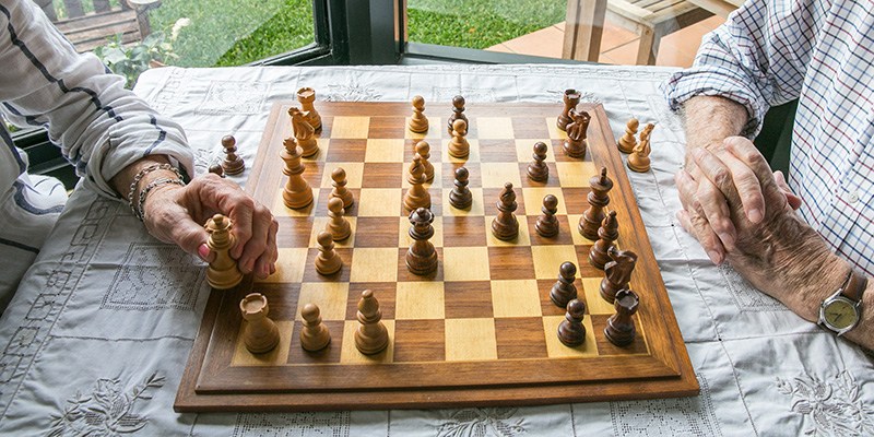 Table game. Male hand adjusting dark pawn on chessboard of players face isn't noticeable